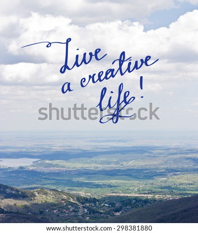 Inspirational phrase 'Live a creative life', written in handwriting on a photo background of blue sky and mountains