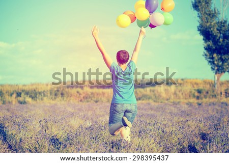 Vintage photo of young woman with colorful balloons in summer field