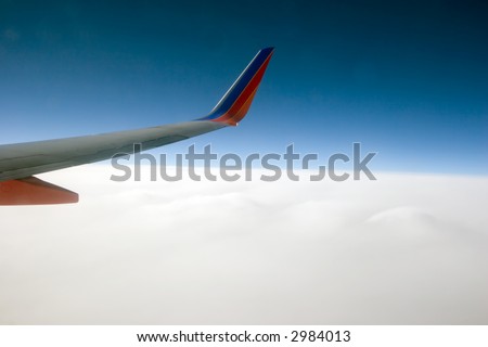 Color DSLR stock picture of the view out the window of a 737 jet airplane flying above the clouds. Travel image. The clear sky above darkens towards space. Horizontal with copy space for text.