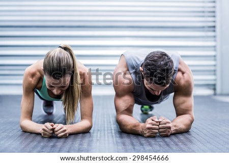 Front view of a muscular couple doing planking exercises Royalty-Free Stock Photo #298454666