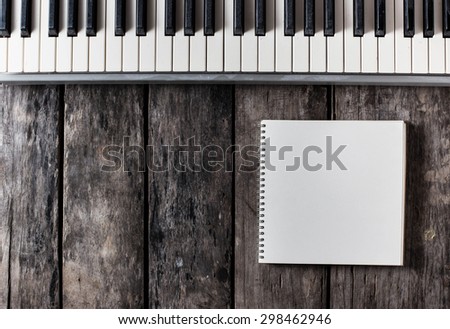 a old piano with note book on wooden background
