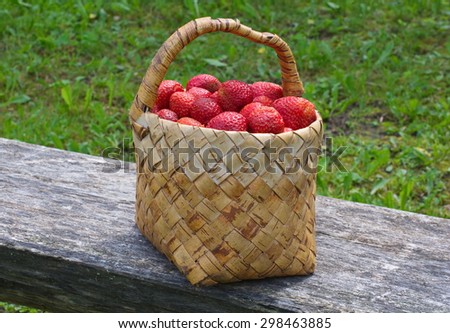 basket filled with fresh strawberries on a wooden bench