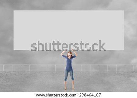 Woman holding blank board standing against the sky.