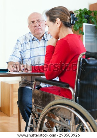 Mature woman in   wheelchair and   elderly man near . 