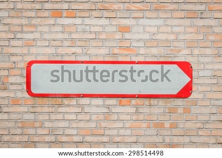Metal sign with an arrow on a brick wall