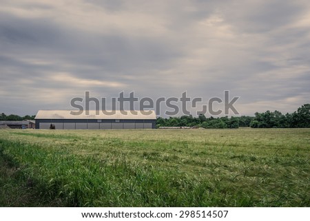 Farm with a barn on a field in cloudy weather