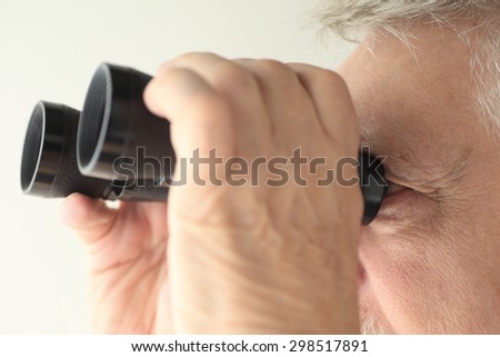 An older man looking through an old pair of binoculars