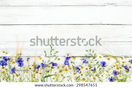 Summer wildflowers and rye on wooden background