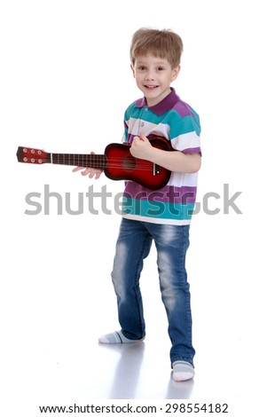 Cheerful little boy in jeans and a striped t-shirt strumming the guitar well, the boy is studying in a music school-Isolated on white background