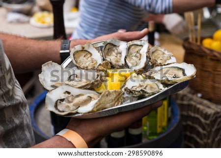 Close Up of Server with Tray of Fresh Shucked Oysters with Lemon Served as Appetizer Royalty-Free Stock Photo #298590896