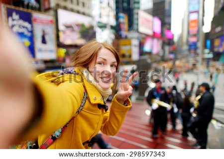 Beautiful young woman taking a selfie with her smartphone on Times Square, New York