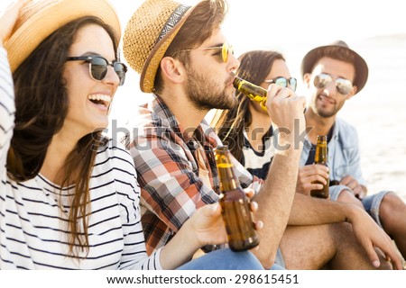 Friends having fun together at the beach and drinking a cold beer Royalty-Free Stock Photo #298615451