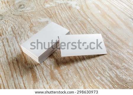 Blank business cards with soft shadows on light wooden background. Template for design presentations and portfolios. Studio shot.