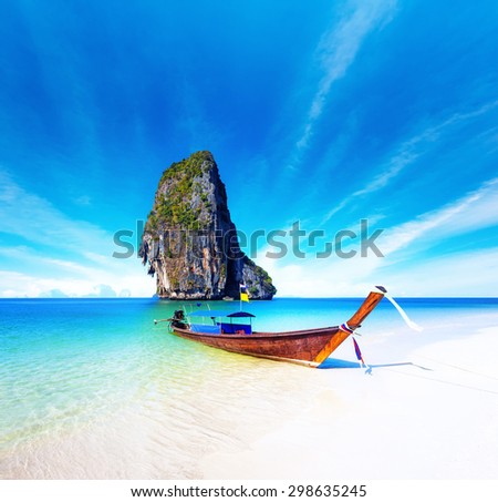 Scenic getaway background of thai boat on exotic beach of tropical island in Thailand. Clear water and blue sky at sunny summer day