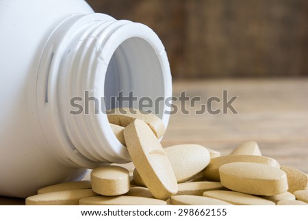 Close up medical pills ,Medicine spilling out of a bottle on wood table
