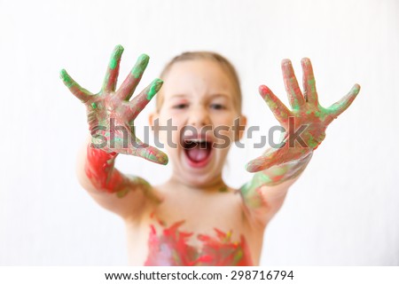 Little girl showing her hands, covered in finger paint after painting a picture and her body with it. Sensory play, permissive upbringing, fun childhood concept, selective sharpness. 