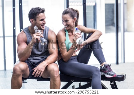 Muscular couple discussing on the bench and holding water bottle Royalty-Free Stock Photo #298755221