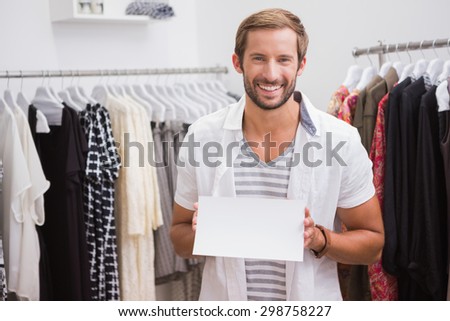 Portrait of smiling man holding blank sign and looking at camera at a boutique