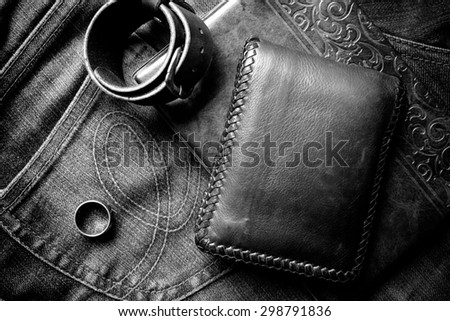 still life photography : Black & white tone leather wallet, Leather wristbands, silver ring and adventure hat on jeans background,  men casual concept, vintage and retro style.