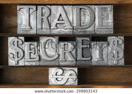 trade secrets phrase with dollar sign made from metallic letterpress type on wooden tray