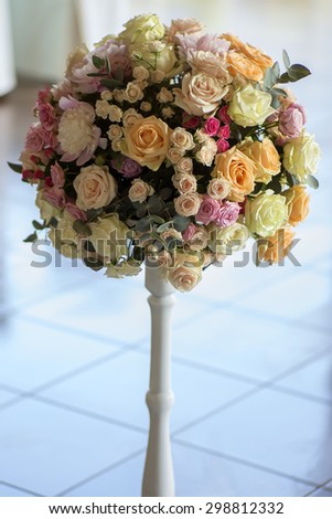 Decorative wedding posy of fresh beautiful flowers of roses and peony white pink violet purple yellow lilac and orange colours in slim long vase on tile floor background, vertical picture