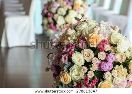 Celebrating hall decorated with wedding bunches of fresh beautiful flowers of roses and peony white pink violet purple yellow lilac and orange colours round shape indoor and chairs, horizontal picture