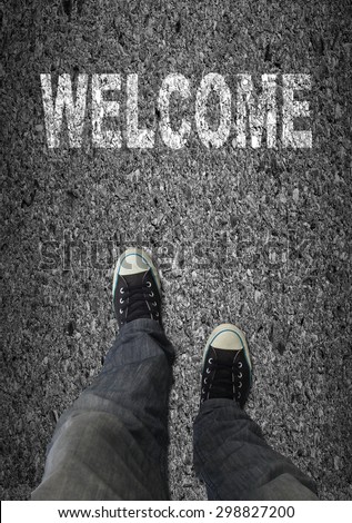 Pair of shoes standing on a road walkway with WELCOME text