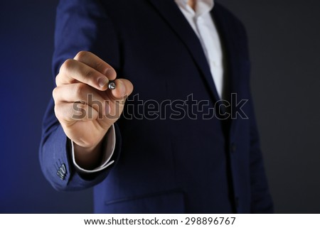 Businessman in suit with pen on dark background