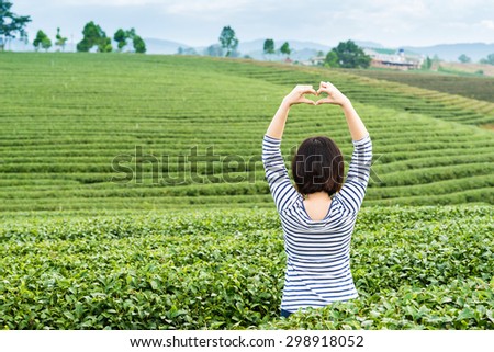 Happy girl acting heart sign in nice tea plantation scene