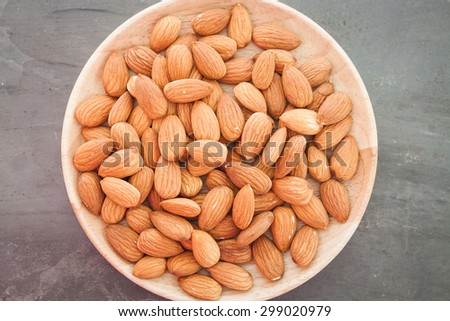Almond nuts on wooden plate, stock photo