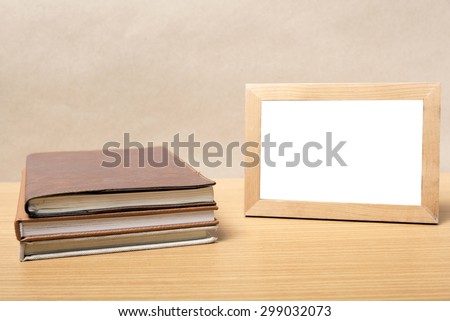 stack of book and photo frame on wood background