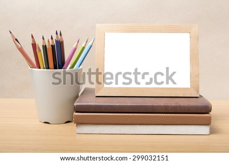 stack of book photo frame with color pencil on wood background