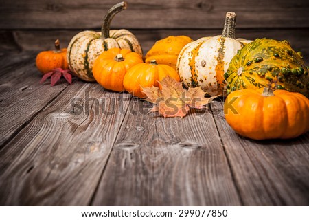 Autumn still life with pumpkins and leaves on old wooden background