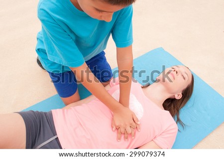 Boy practicing CPR with a woman on the floor. Royalty-Free Stock Photo #299079374