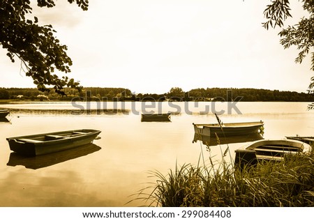 Vintage photo of old boats for fishing on the lake, quiet surface of water. Nature background or landscape, vintage effect.