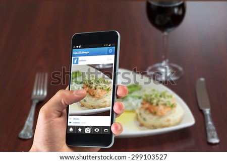 hand holding smartphone against front view of salmon dish with asparagus