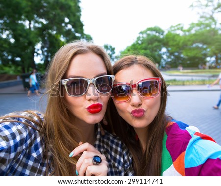 Close up lifestyle selfie portrait of two young positive woman having fun and making selfie, teenage hipster trendy clothes and sunglasses, long hairs,bright make up. happy together. sisters, friends