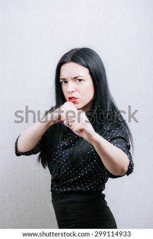 Woman calls to a fight with his fists. On a gray background.