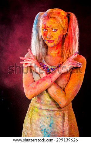 Beautiful young woman covered with colored powder over dark background