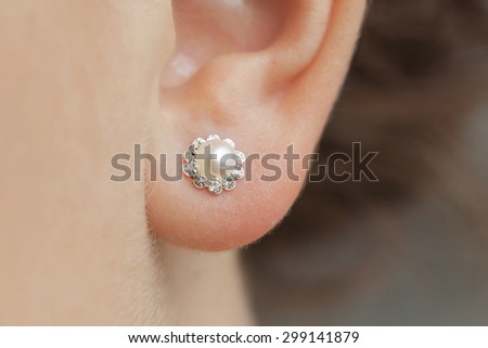 woman's ear with an earring Royalty-Free Stock Photo #299141879