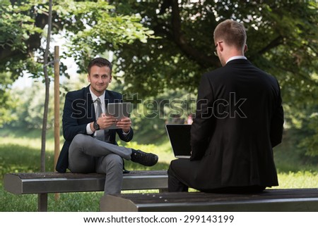 Happy Business Men Using Tablet Pc Outside On A Park Bench
