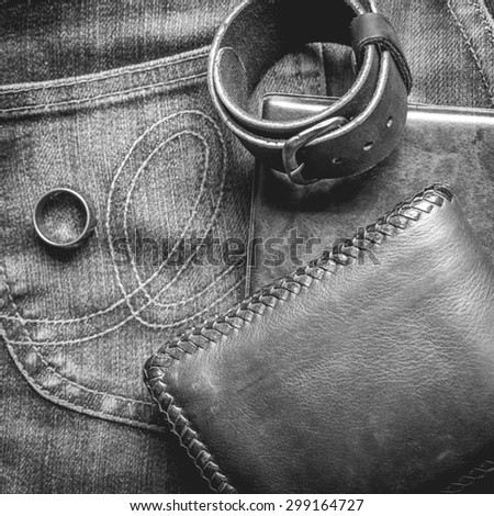 still life photography : Black and White tone leather wallet, Leather wristbands, silver ring and adventure hat on jeans background, men casual concept, vintage and retro style