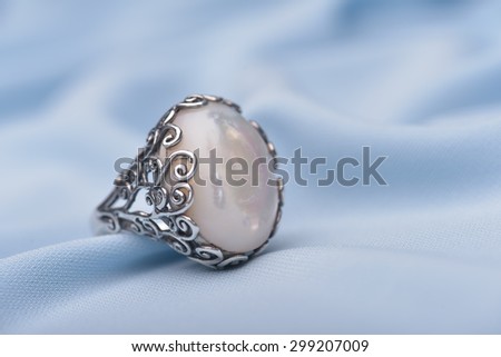 Exquisite silver ring with stone against light blue background 