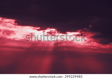 Sun rays glowing through the clouds. Dramatic lighting before a storm. Apocalypse concept. Toned photo.