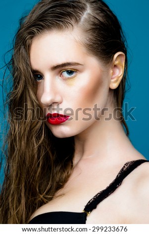 Portrait of beautiful young woman with fresh clean skin and red lips on blue background