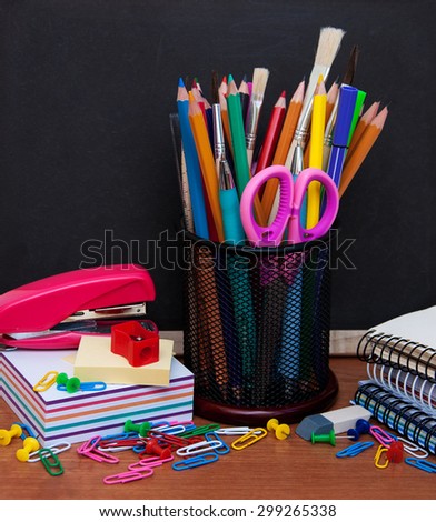 school supplies on a wooden table and  blackboard