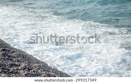 Sea wave foam on the pebble beach.