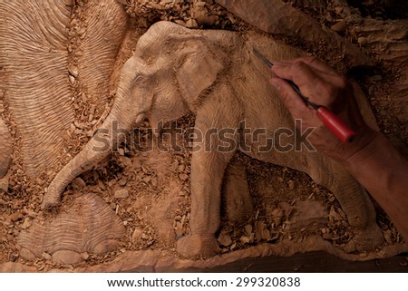 The close up carver or engraver are doing handicraft wooden elephant. 