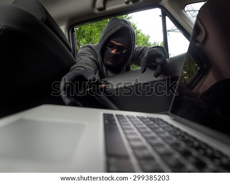 Crime concept - thief stealing laptop from the car. View from laptop Royalty-Free Stock Photo #299385203