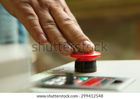Male hand pushing emergency red stop button. Royalty-Free Stock Photo #299412548